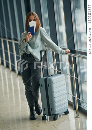 In corridor with tickets and luggage bag. Young woman in airport hall In corridor with tickets and luggage bag. Young woman in airport hall 130181825