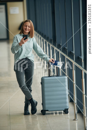 Luggage bag and smartphone. Young woman in airport hall 130181831