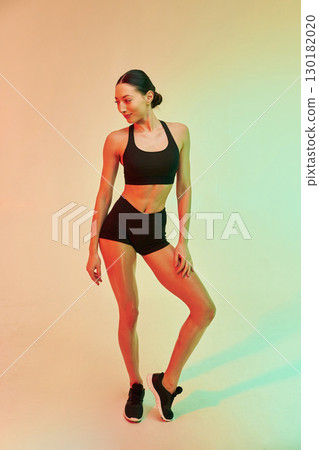 In black sportive clothes. Young fitness woman is against background in studio 130182020