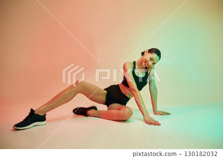Against colorful background. Young fitness woman in sportive clothes in studio 130182032