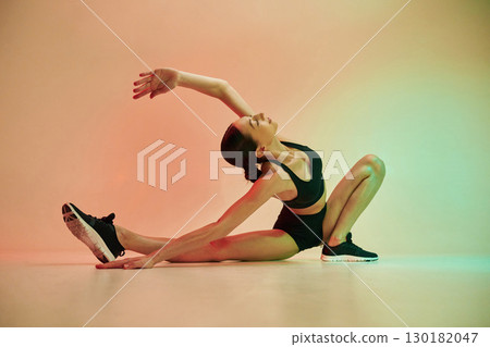 Showing flexibility. Young fitness woman in sportive clothes against background in studio Showing flexibility. Young fitness woman in sportive clothes against background in studio 130182047