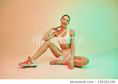 Looking forward. Young fitness woman in sportive clothes against background in studio Looking forward. Young fitness woman in sportive clothes against background in studio 130182106