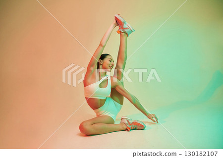 Flexible body type. Young fitness woman in sportive clothes against background in studio Flexible body type. Young fitness woman in sportive clothes against background in studio 130182107