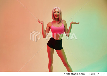Smiling, positive facial expression. Sportive woman with pink wig is against background Smiling, positive facial expression. Sportive woman with pink wig is against background 130182110