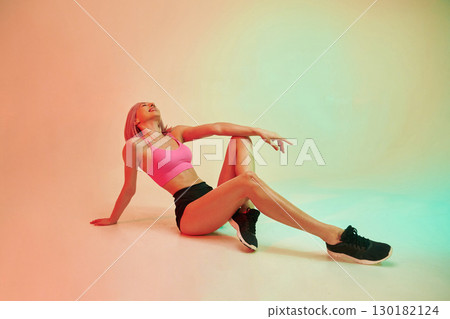 Sitting on the floor. Sportive woman with pink wig is against background Sitting on the floor. Sportive woman with pink wig is against background 130182124