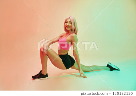 Cheerful facial expression. Sportive woman with pink wig is against background Cheerful facial expression. Sportive woman with pink wig is against background 130182130