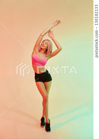 With hands up. Sportive woman with pink wig is against background 130182133