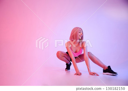 Soft pink lighting. Sportive woman with wig is against background Soft pink lighting. Sportive woman with wig is against background 130182150