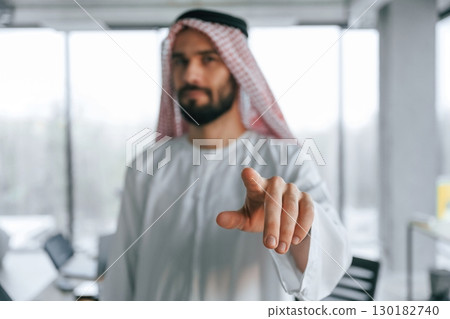 In traditional outfit. Successful Muslim businessman is in his office In traditional outfit. Successful Muslim businessman is in his office 130182740