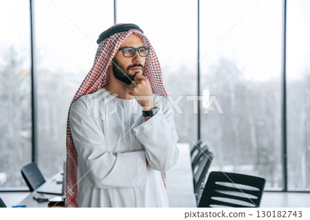 Young investor is standing. Successful Muslim businessman in traditional outfit in his office 130182743