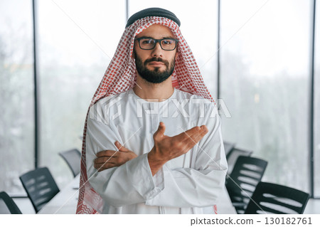 Doing gestures by hands. Successful Muslim businessman in traditional outfit in his office Doing gestures by hands. Successful Muslim businessman in traditional outfit in his office 130182761