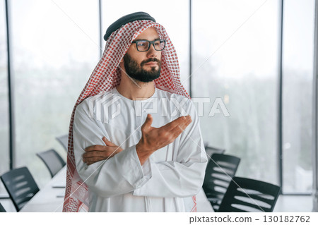 Doing gestures by hands. Successful Muslim businessman in traditional outfit in his office 130182762