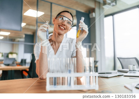 Working with bunch of test tubes. Female doctor in white coat is indoors 130183356