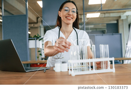 Empty test tubes on the table. Female doctor in white coat is indoors Empty test tubes on the table. Female doctor in white coat is indoors 130183373