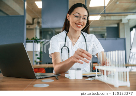 Professional practitioner. Female doctor in white coat is indoors 130183377