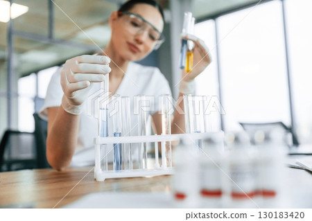 Yellow liquid in the test tube. Female doctor in white coat is indoors Yellow liquid in the test tube. Female doctor in white coat is indoors 130183420
