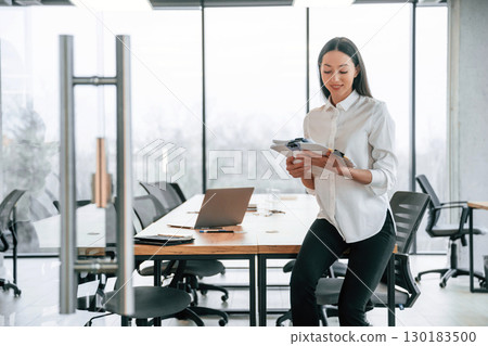 Against big panoramic windows. Businesswoman is indoors in the office 130183500
