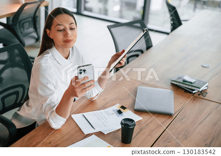Many of the documents and objects on the table. Businesswoman is indoors in the office 130183542