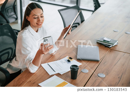 Many of the documents and objects on the table. Businesswoman is indoors in the office 130183543