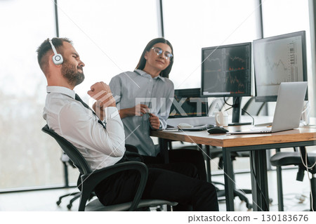 Man is in headphones. Two employees are working in the office together Man is in headphones. Two employees are working in the office together 130183676