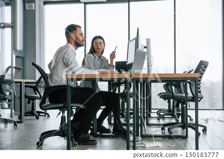 Analyzing information. Two employees are working in the office together 130183777