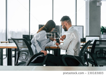 Stock information, using smartphone. Two employees are working in the office together 130183803