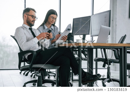 Man is using smartphone. Two employees are working in the office together 130183819