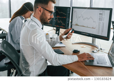 Focused on a project. Two employees are working in the office together 130183824