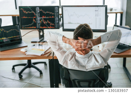 Sitting with hands behind the head. Businessman is by computer and working in the office Sitting with hands behind the head. Businessman is by computer and working in the office 130183937