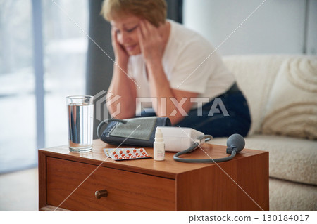 Sick, feeling bad. Pills on the table. Senior elderly woman is at home in the living room Sick, feeling bad. Pills on the table. Senior elderly woman is at home in the living room 130184017