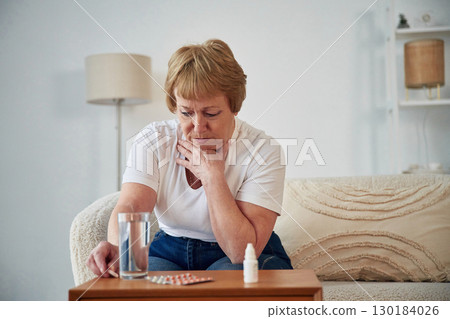 Taking the medicine, conception of illness. Senior elderly woman is at home in the living room 130184026