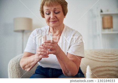 Self medicate. Taking medicine. Senior elderly woman is at home in the living room Self medicate. Taking medicine. Senior elderly woman is at home in the living room 130184033