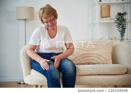 Pain in the leg. Senior elderly woman is at home in the living room Pain in the leg. Senior elderly woman is at home in the living room 130184046