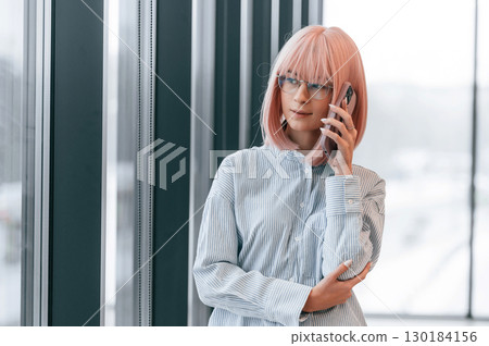 Talking by phone. Woman with pink hair is in the office. Young worker Talking by phone. Woman with pink hair is in the office. Young worker 130184156