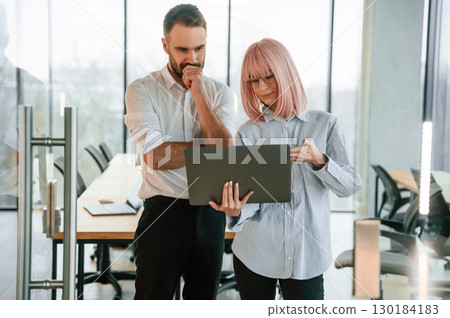 Using laptop. Man and woman are working in the office together Using laptop. Man and woman are working in the office together 130184183