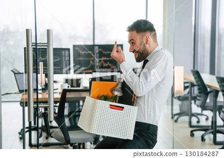 Showing middle finger. Unemployed man is with personal belongings after being fired Showing middle finger. Unemployed man is with personal belongings after being fired 130184287