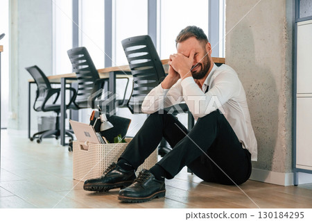 Depressed, sitting on the floor. Unemployed man is with personal belongings after being fired 130184295