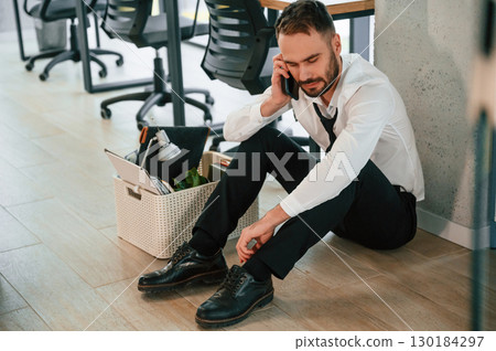 Depressed, sitting on the floor. Unemployed man is with personal belongings after being fired 130184297