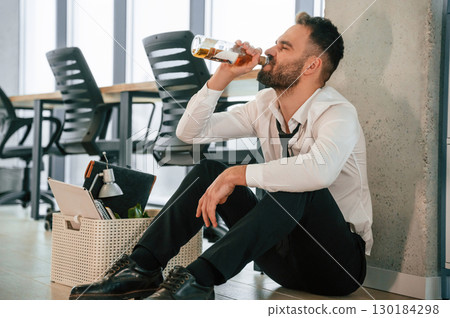 Drinking alcohol. Unemployed man is with personal belongings after being fired Drinking alcohol. Unemployed man is with personal belongings after being fired 130184298
