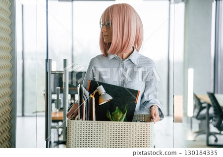 Unemployed woman with pink hair is with personal belongings after being fired 130184335