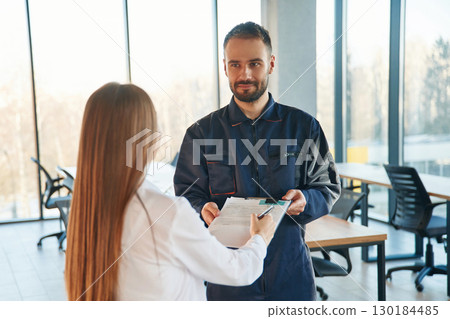 Sign this document. Man and woman employees are working in the office 130184485