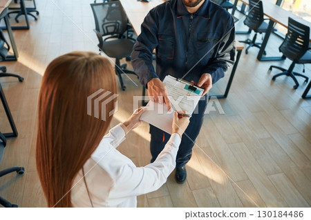 Sign this document. Man and woman employees are working in the office Sign this document. Man and woman employees are working in the office 130184486
