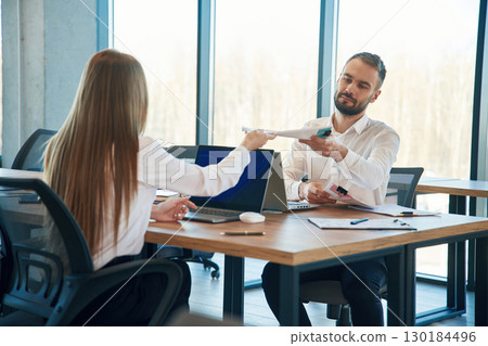 Working together. Man and woman employees are in the office Working together. Man and woman employees are in the office 130184496