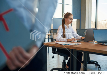Holding gift box for woman. Two employees are working in the office 130184540