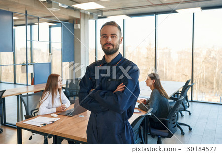 Repairman is standing in the office, employees behind Repairman is standing in the office, employees behind 130184572