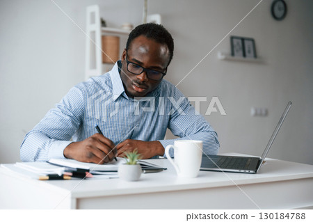 Doing some paperwork. Businessman is in the office by laptop Doing some paperwork. Businessman is in the office by laptop 130184788