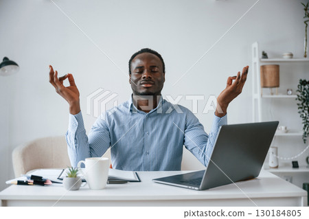 Meditating, mental health is important. Businessman is working in the office by laptop Meditating, mental health is important. Businessman is working in the office by laptop 130184805