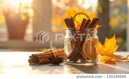 秋日陽光下的桌子上,玻璃罐裡放著肉桂棒和乾橙子 秋日陽光下的桌子上,玻璃罐裡放著肉桂棒和乾橙子 130184894