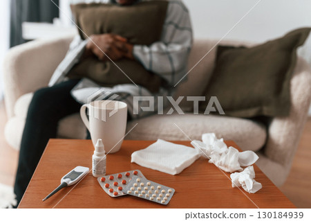 Close up view of bunch of pills on table. Sick black man is at home Close up view of bunch of pills on table. Sick black man is at home 130184939