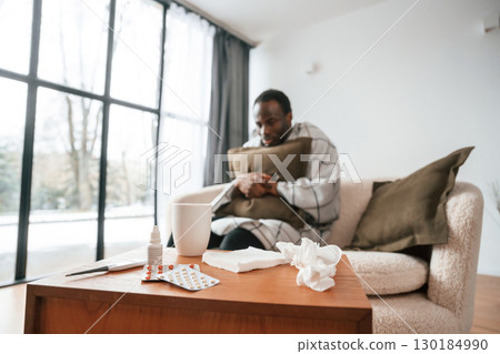 Sitting on sofa, holding pillow. Sick black man is at home Sitting on sofa, holding pillow. Sick black man is at home 130184990